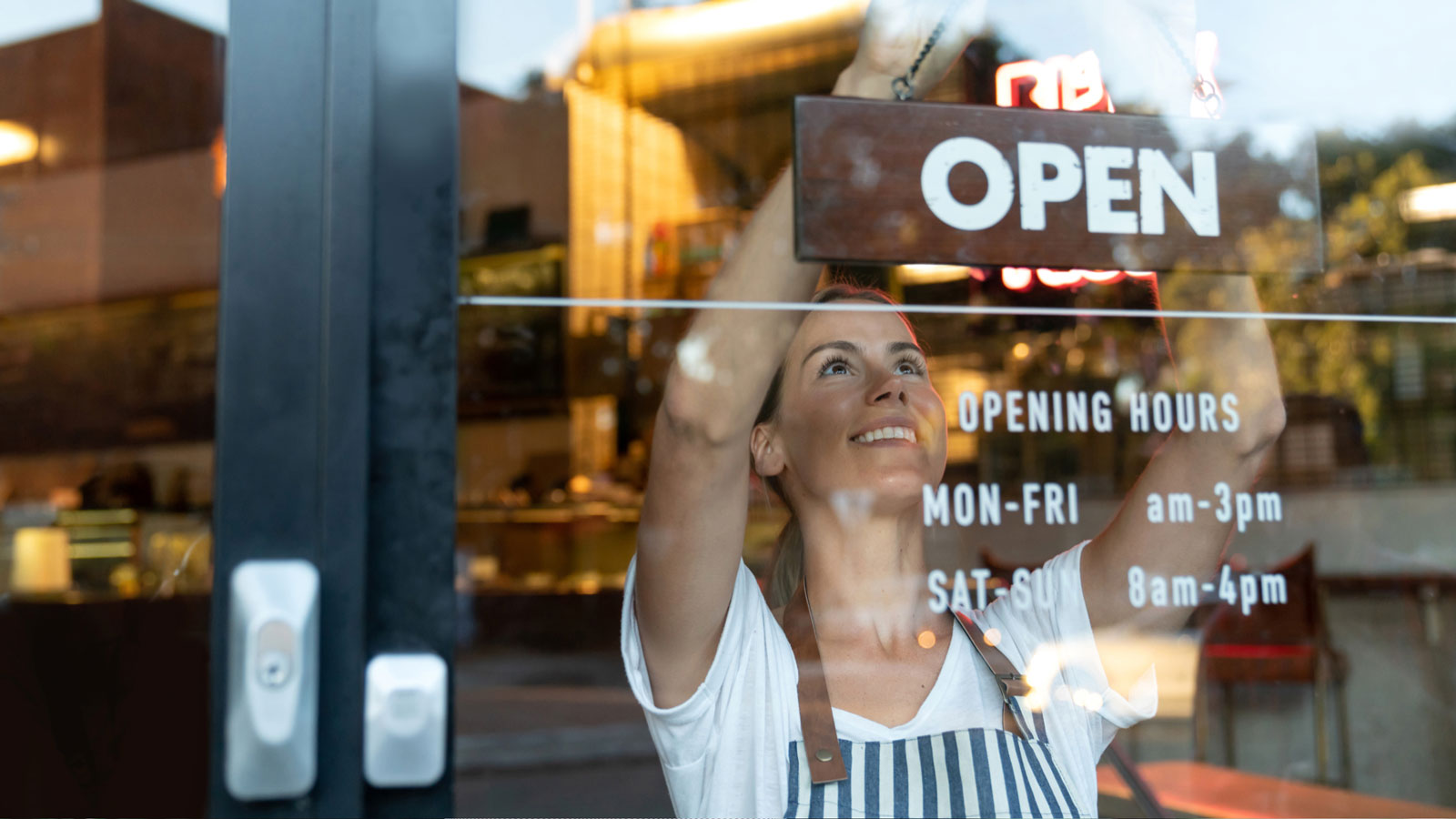 woman hanging an open sign