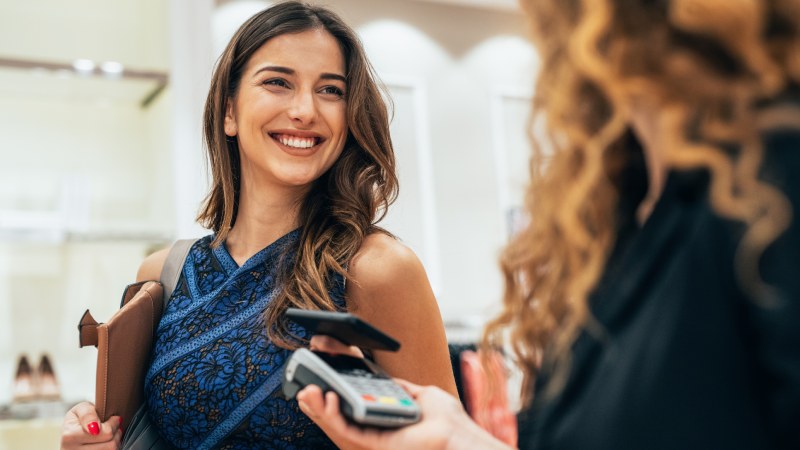 Woman smiling, paying with her card in store.